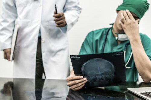 Doctor looking at X-rays of patients head, being told he made a mistake