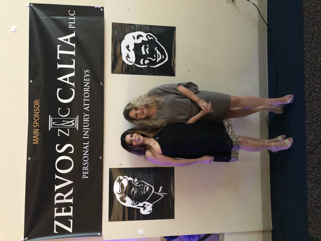 Angela Zervos and Lauren Calta posing in front of banner at fundraising event for Shepherd Center