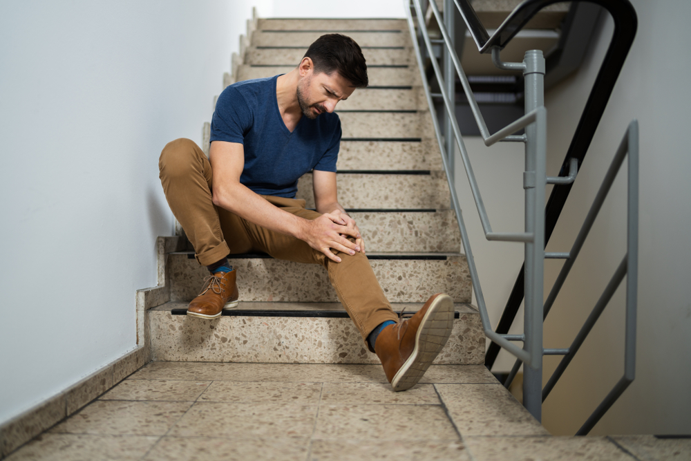 Man in Tarpon Springs sitting on stairs after a slip and fall injury on a business premises.