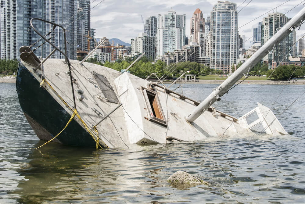 Boat is sinking near the shore of city.