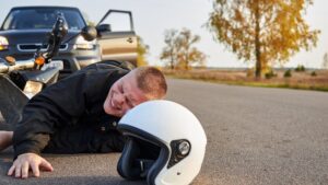 Motorcycle rider in pain after collision of car.