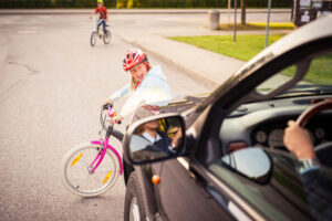 Scared child on wheels about to get hit by a car.