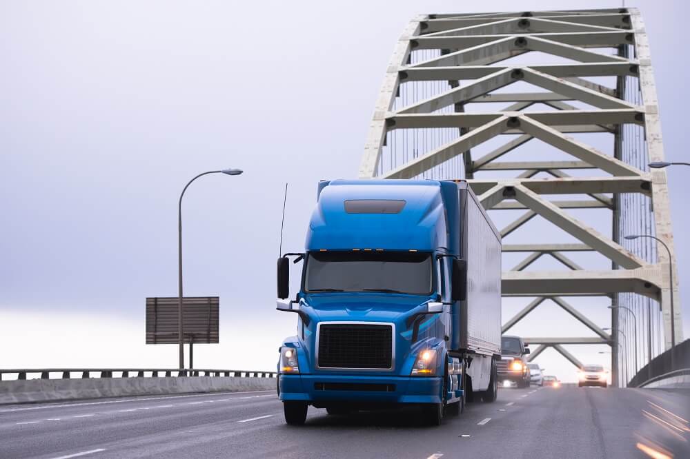 Blue truck passing the bridge.