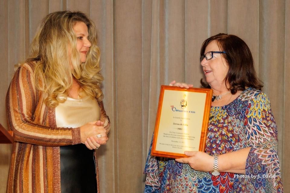 Lauren Calta on stage accepting award from presenter at Wheelchairs 4 Kids charity event