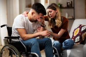 Spouse comforting her husband on wheelchair.