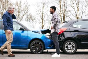 Drivers in car collision discussing how to settle accident.