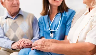 Healthcare professional holding hands with two elderly patients in a supportive gesture.