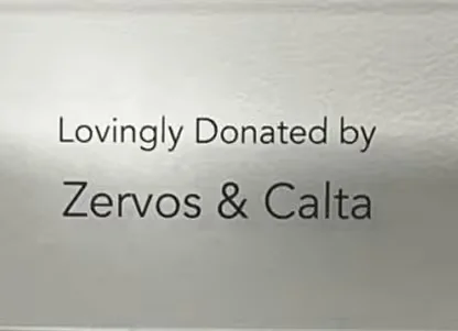 Inscription reading 'Lovingly Donated by Zervos & Calta' on a light-colored surface.