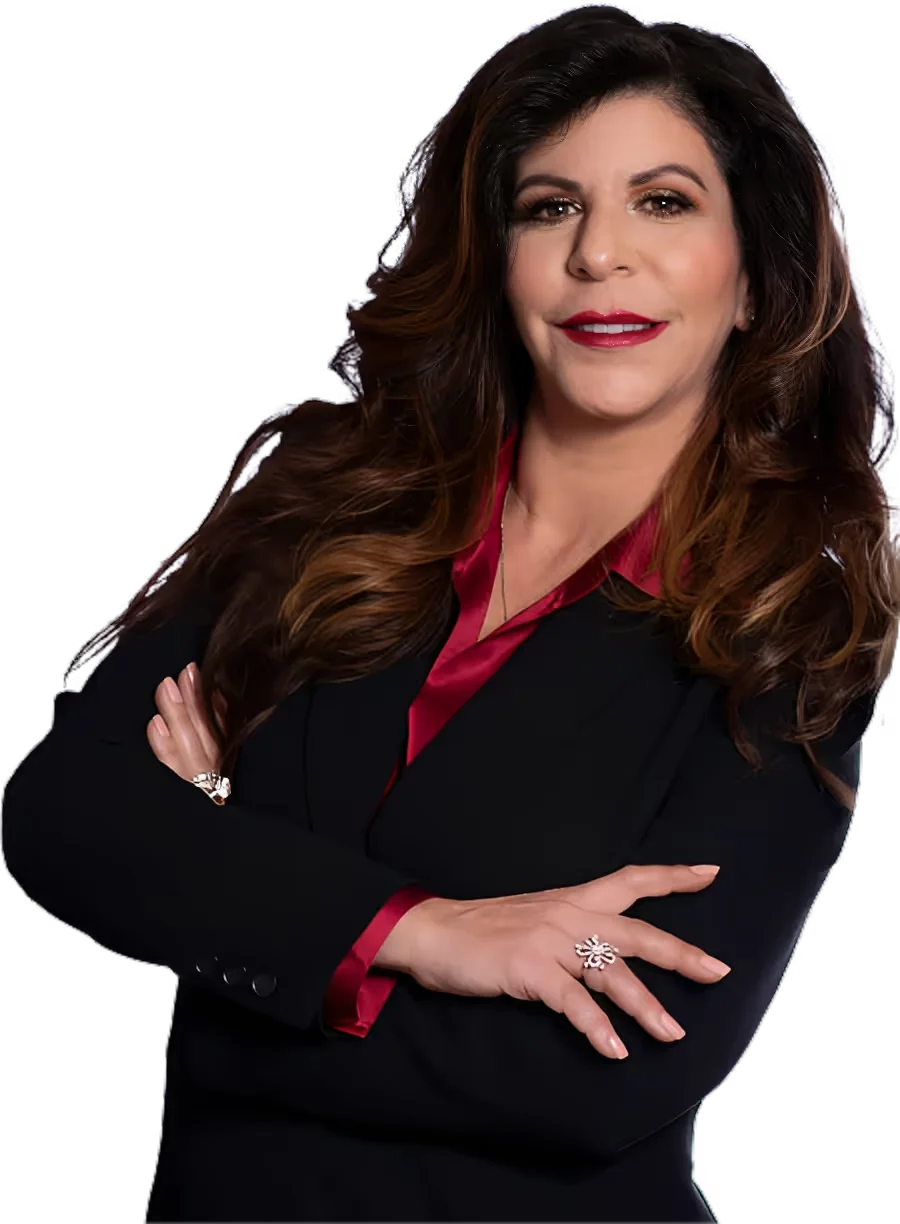 Confident woman with long wavy brown hair in a black blazer over a red blouse, arms crossed.